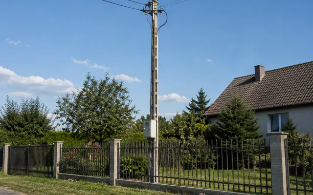 Betonowy słup energetyczny średniego napięcia przy granicy działki